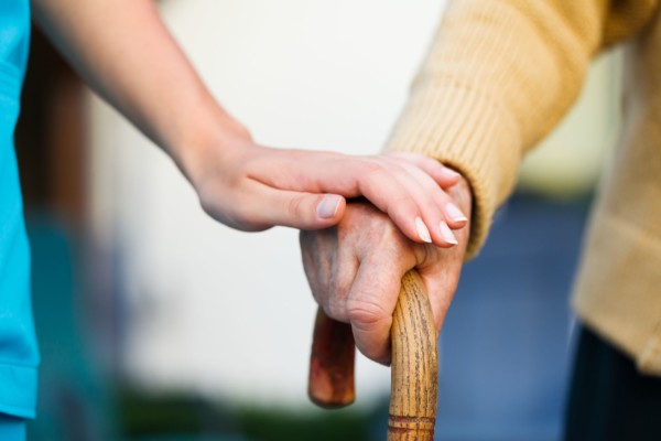 Doctor holding a senior patiens's hand on a walking stick