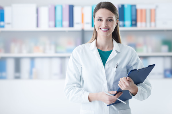 Smiling young female doctor holding a clipboard, healthcare concept